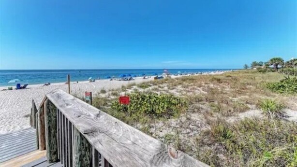 Una playa con un paseo marítimo de madera y sillas de playa.