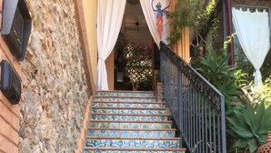 Un escalier orné de carreaux colorés et à motifs, menant à l’entrée d’un immeuble.