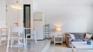 Un salon moderne avec un canapé blanc, une table basse et un coin repas comprenant des chaises et une table.