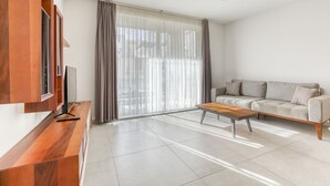 A modern living room with a sofa, coffee table, and TV on a wooden console.