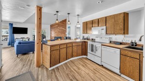 A modern kitchen with wooden cabinets, a built-in island, white appliances, and pendant lighting.