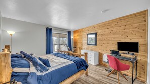 A bedroom with a wooden bed, a desk with a computer, and a chair.