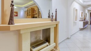 A modern interior with a fireplace, decorative statues, and a hallway with arched ceilings.