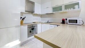 A modern kitchen with white cabinets, a built-in oven, a microwave, and a coffee maker. - Spacious, central APT in Paceville/St Julians (San Ġiljan)