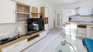 A modern kitchen with a built-in oven, a dining area with bar stools, and a small seating area with a glass table. - Spacious, central APT in Paceville/St Julians (San Ġiljan)