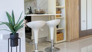 A modern kitchen with white bar stools, a marble backsplash, and a wooden cabinet. - A lovely designer Apt with Balcony in St` Julians (St. Julian`s)