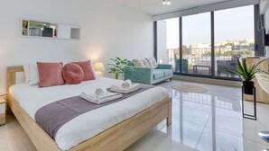 A modern bedroom with a large bed, a sofa, and a balcony with a view. - A lovely designer Apt with Balcony in St` Julians (St. Julian`s)