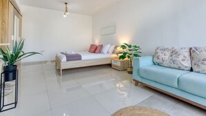 A modern bedroom with a bed, bedside table, and a light blue sofa. - A lovely designer Apt with Balcony in St` Julians (St. Julian`s)