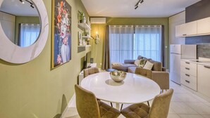 A modern living room with a round dining table, sofas, a large mirror, and a painting on the wall. - Modern & private 1BR APT in the Heart of Paceville (St. Julian`s)