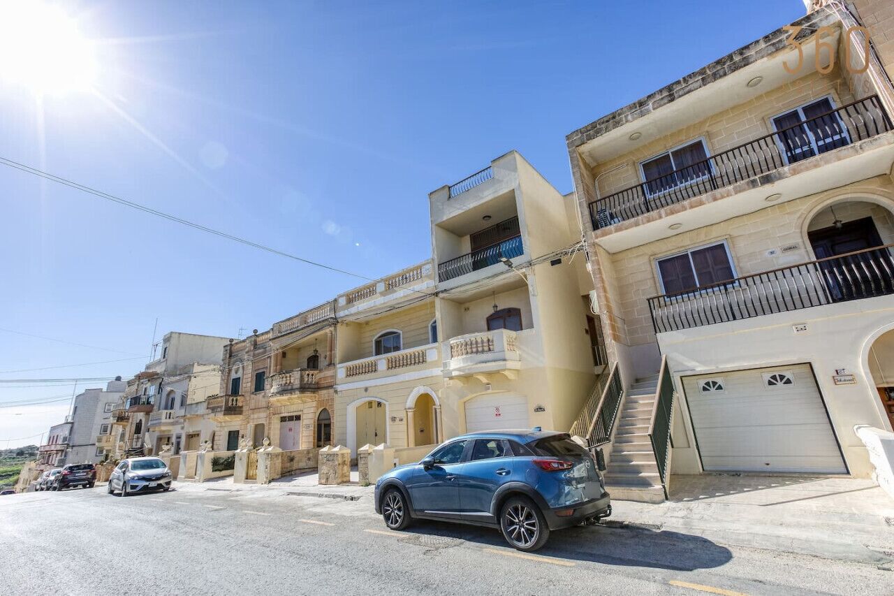 A multi-story building with balconies, a garage, and a parked car.