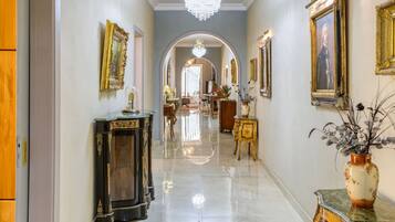 A hallway with ornate furniture, a chandelier, and framed artwork on the walls.
