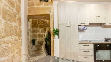 A modern kitchen with a stone wall, a built-in oven, and a dining area with a glass table.