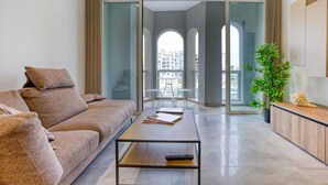 A modern living room with a sofa, a coffee table, and a view of a balcony with a pool.