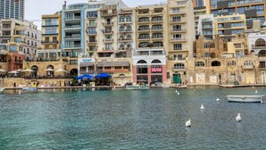 A waterfront area with buildings, a marina, and a restaurant with outdoor seating.