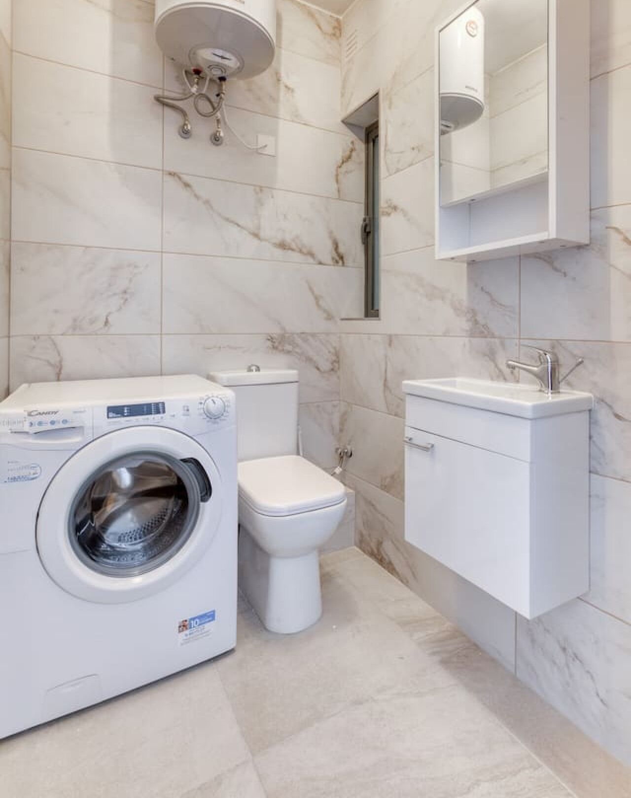 A modern bathroom with a washing machine, toilet, and sink.