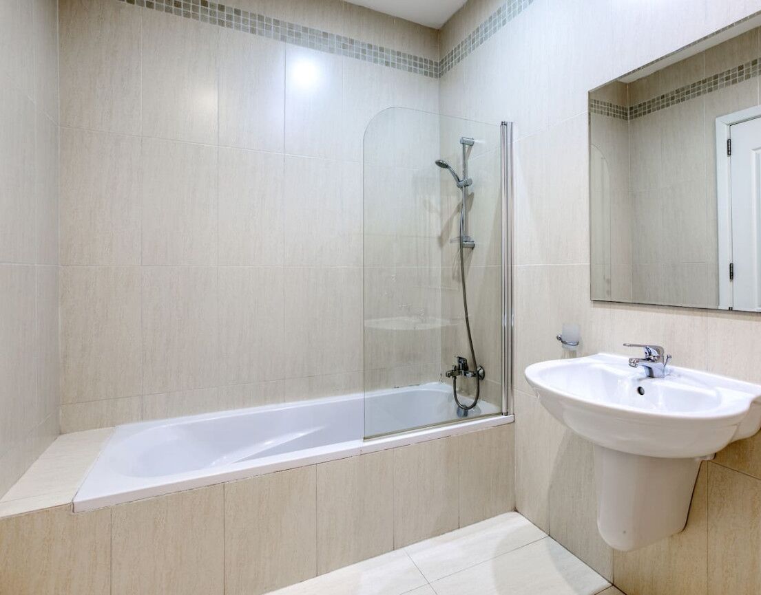 A modern bathroom with a glass-enclosed shower, a white bathtub, and a sink.