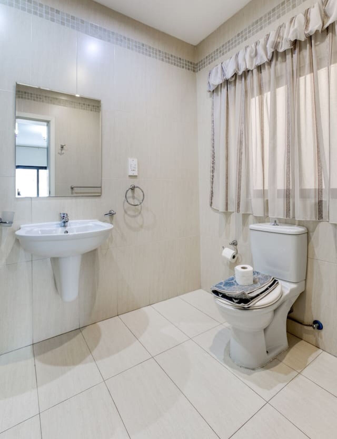 A bathroom with a sink, toilet, and mirror.
