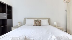A modern hotel room with a large bed, two bedside tables, a wardrobe, and a view of the sea. - Cosy 1BR penthouse with Private Terrace in Gzira (Il-Gżira)