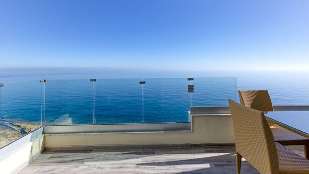 A balcony with a clear view of the ocean, a glass table, and wicker chairs. - Seafront 3BR APT in Sliema with Private Balcony (Sliema)