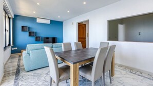 A modern room with a dining table, chairs, a sofa, and a large mirror on the wall. - Seafront 3BR APT in Sliema with Private Balcony (Sliema)