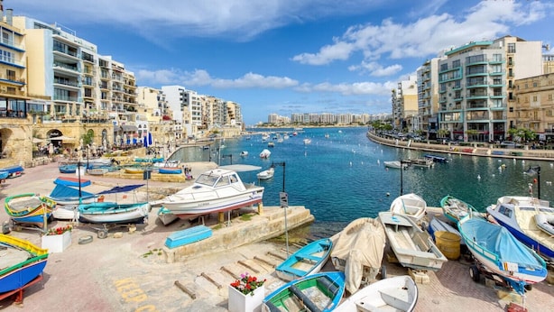 Un puerto deportivo con barcos amarrados, rodeado de edificios de varios pisos con balcones.
