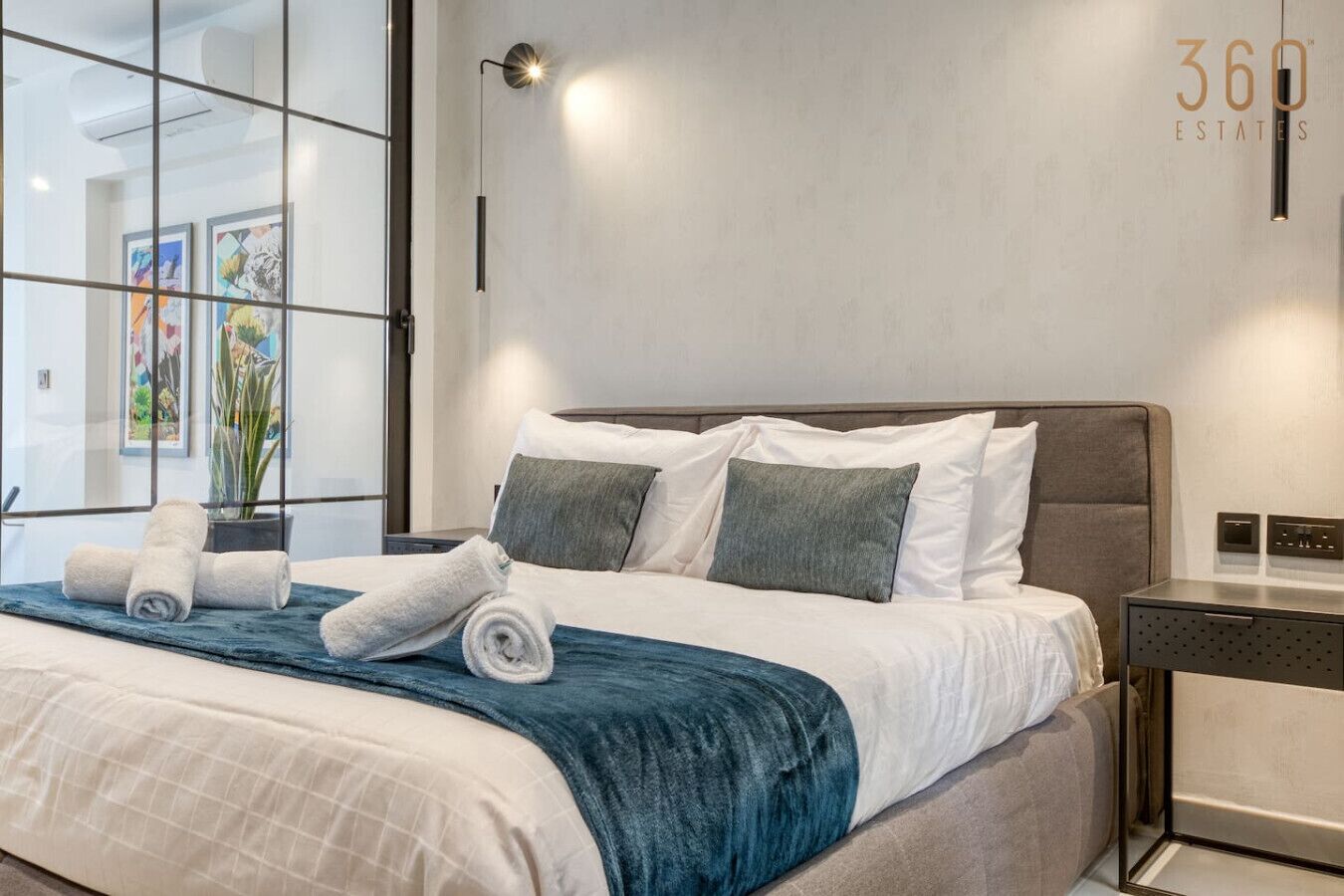 Ein modernes Hotelzimmer mit einem großen Bett, einem Nachttisch und einer Wandleuchte.