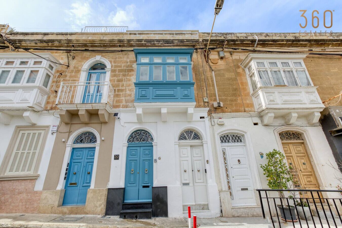 A row of traditional Mediterranean-style buildings with blue and white doors, balconies, and a clear sky.