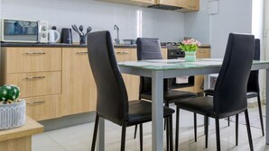 Eine moderne Küche mit Holzausstattung, einer Mikrowelle, einer Kaffeemaschine und einem Esstisch mit vier Stühlen.