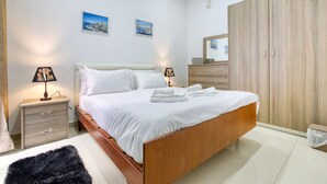 Ein Schlafzimmer mit einem Bett, Nachttischen, einem Kleiderschrank und zwei Bildern an der Wand.