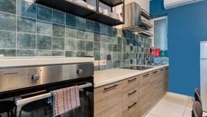 A modern kitchen with a built-in oven, stainless steel appliances, and a blue tiled backsplash. - Modern 3BR Apt with private terrace & BBQ in Gzira (Il-Gżira)