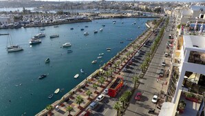 A marina with boats, a parking area, and a road with vehicles.