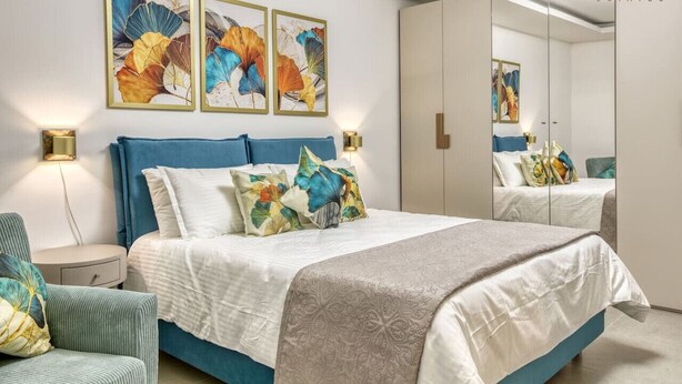 A bedroom with a bed, bedside tables, a chair, and a large mirror. - Beautiful 3BR home in charming Marsascala w/WIFI (Wied il-Għajn)