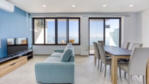 Un salon moderne comprenant un canapé, un téléviseur, une table à manger et des chaises.