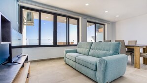 Un salon moderne avec un canapé bleu clair, une table à manger en bois et un téléviseur à écran plat posé sur un meuble.