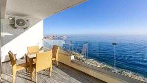 Un balcon doté de meubles en osier, offrant une vue sur la côte.