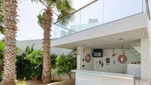 Un espace d’accueil moderne avec un comptoir en verre, des palmiers et divers éléments décoratifs disposés sur le mur.