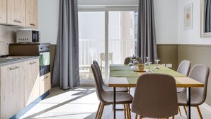 A modern kitchen with a microwave, oven, and cabinets. There is a dining table with chairs and a view of the balcony. - Stylish 2BR home with Balcony in central Pieta (Tal-Pietà)