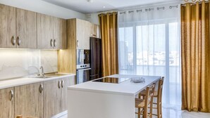 A modern kitchen with wooden cabinets, a central island, and a large window with curtains.