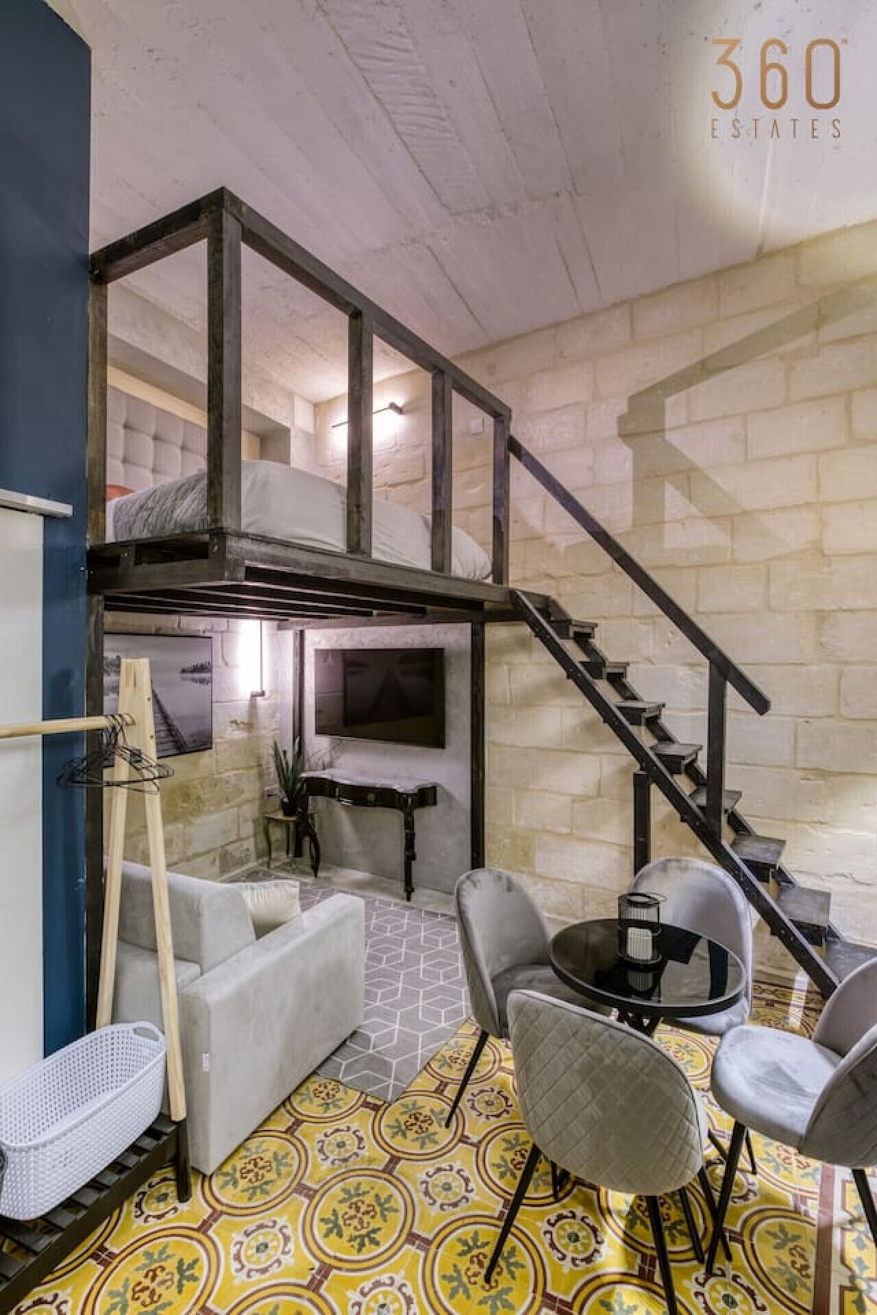 Une pièce de style loft avec un escalier, un canapé, une table basse et un téléviseur.
