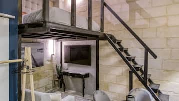 Une pièce de style loft avec un escalier, un canapé, une table basse et un téléviseur.