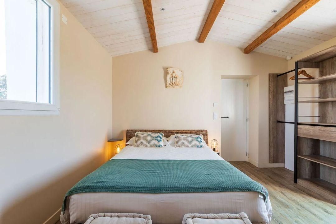 Een slaapkamer met een bed, een houten plafond, een kunstwerk aan de muur en een kledingkast.