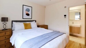 A bedroom with a bed, bedside table, lamp, and a framed picture on the wall.
