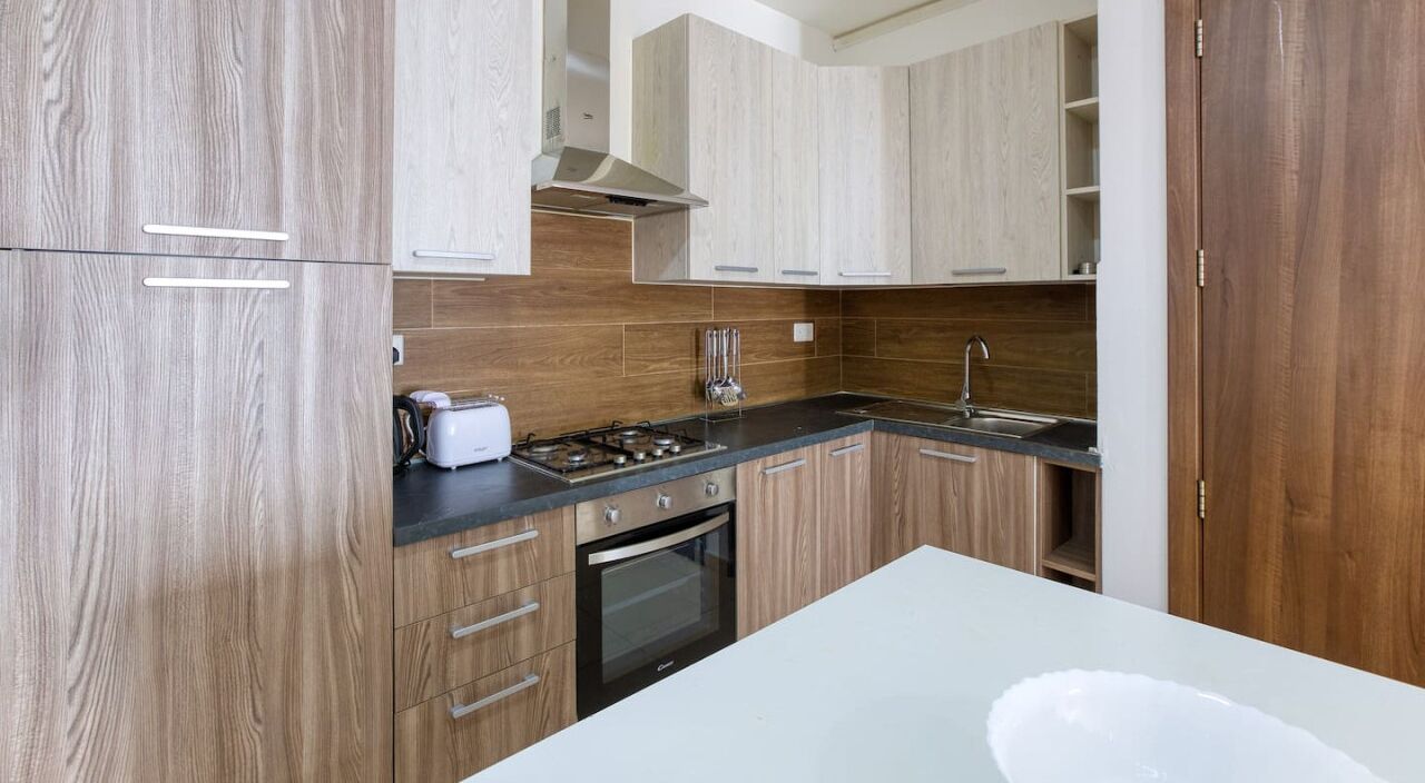 Une cuisine moderne avec des meubles en bois, une cuisinière à gaz, un grille-pain et un évier.