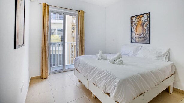 A bedroom with a bed, a painting of a tiger, and a sliding glass door to a balcony. - Spacious 4BR home with private balcony in Swieqi (Is-Swieqi)