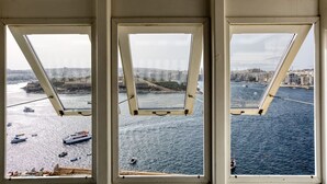 A view from a high-rise building with multiple windows overlooking a body of water and a cityscape.