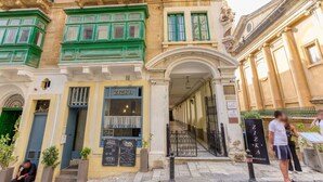 A building with a restaurant named "ZIZKA" on the ground floor, featuring a traditional facade with green window frames and a classical entrance.