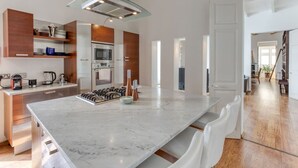 A modern kitchen with a marble countertop, stainless steel appliances, and a wooden accent wall.