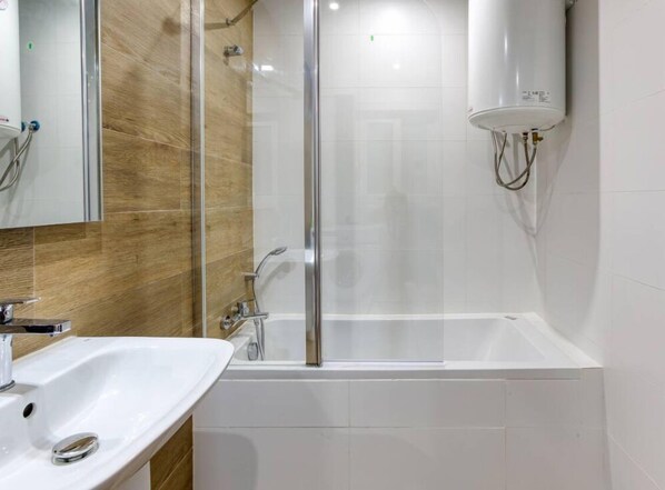 A modern bathroom with a glass-enclosed shower, a white bathtub, and a sink with a chrome faucet. - Lovely Studio Apt with Private Balcony in Pieta (Tal-Pietà)