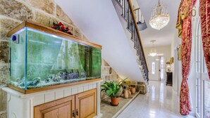 A spacious hallway with a large fish tank, a staircase, and a chandelier.