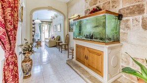 A spacious hallway with a large fish tank, a decorative vase, and a cozy seating area.